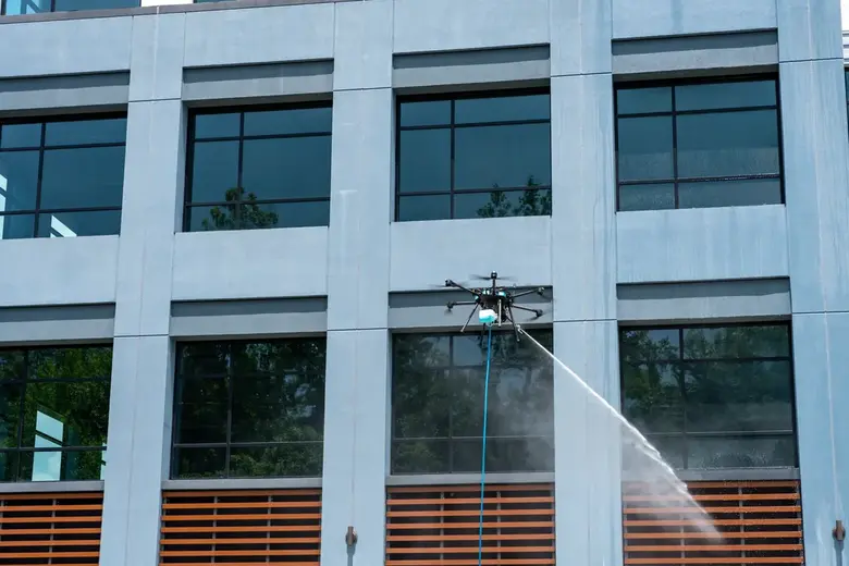 Drone pressure washing a building facade